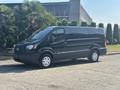 A 2016 Ford Transit 150 van in black color with a sliding door and alloy wheels parked on a paved surface