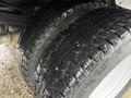 A close-up view of two heavy-duty tires from a 2008 Ford F-350 showing deep treads and wet surfaces