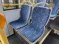 Two blue bus seats with a geometric design, featuring light-colored patterns, set in the interior of a vehicle designed for public transport