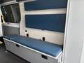 Interior view of a 2020 Mercedes-Benz Sprinter 2500 featuring blue padded seating and storage compartments along the side wall