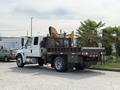 A 2011 International 4300 truck with a flatbed and a mounted construction equipment attachment at the back