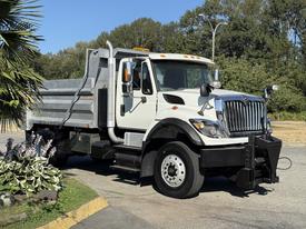 A 2011 International Workstar dump truck with a white and silver body and a plow attachment in the front