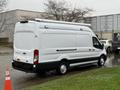 A white 2023 Ford Transit van parked at an angle with sliding doors and a high roof design