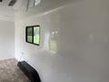 Interior view of a 2025 Shuttle Office with glossy white walls and a black storage unit against the wall