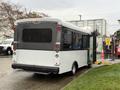 A 2019 Chevrolet Express bus with a gray and white exterior and a side entry ramp is parked with its back facing the viewer