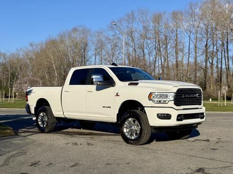 A 2023 RAM 3500 pickup truck in white with chrome accents parked on a street with a clear view of its front and side features