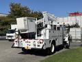A 2010 International 4300 utility truck with a large bucket lift attached at the rear designed for aerial work operations