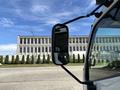 A 2018 Hino 195 truck with a side mirror reflecting the building behind it