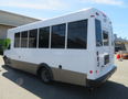 A white 2020 Chevrolet Express bus with large windows and a gray stripe along the bottom is shown from the rear angle