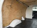Interior of a 2008 Ford Econoline van featuring bare wood paneling on the walls and a rubber floor mat with visible wear