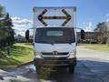 A 2014 Hino 195 truck with a large white box cargo area and yellow reflective markings on the back facing forward