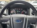 Dashboard of a 2014 Ford F-150 displaying gauges and controls with a steering wheel featuring the Ford logo