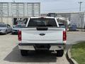 A white 2021 Ford F-150 viewed from the rear with a chrome bumper and tailgate featuring the Ford logo and F-150 emblem