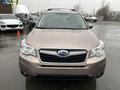 A 2016 Subaru Forester in a light brown color with a prominent front grille and the Subaru emblem in the center