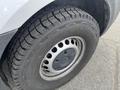 A close-up of a tire from a 2025 Mercedes-Benz Sprinter showing robust tread design and a silver wheel rim with a prominent Mercedes-Benz logo