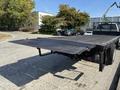 A 2018 Ford F-750 flatbed truck with a lowered loading ramp in the foreground