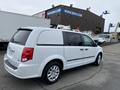 A white 2014 RAM Cargo Van with a streamlined design and rear windows covered, parked at a commercial location