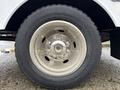 A close-up of a wheel from a 2000 Ford F-450 showing a polished silver rim and a black tire with visible tread pattern