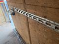 A close-up view of a wooden interior wall of a 2016 Continental cargo trailer featuring a metal track with multiple slots for securing cargo and a round mirror attached