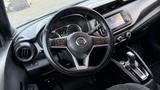 The interior of a 2019 Nissan Kicks featuring a black steering wheel with controls and a dashboard displaying a digital speedometer and a central touchscreen display