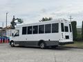 A white 2020 Chevrolet Express bus with large windows and a black lower body parked at an angle