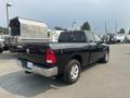 A black 2015 RAM 1500 pickup truck viewed from the rear showing its taillights and cargo bed