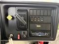 The dashboard of a 2013 International 4300 featuring a gear shift lever a series of buttons for various functions and a Panasonic stereo system