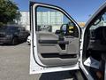 A 2019 Ford F-550 truck with the driver's door open showing the interior handle and control panel