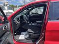 A red 2015 Jeep Grand Cherokee with an open door showing the interior including the dashboard steering wheel and front seats