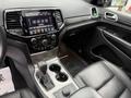 Interior of a 2019 Jeep Grand Cherokee showcasing a black leather dashboard console with a touchscreen display and gear shifter