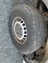 A close-up view of a 2016 Mercedes-Benz Sprinter tire showing a steel rim with multiple holes and worn rubber tread