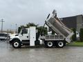 A white 2011 International 7500 dump truck with its bed raised showing it is in the process of unloading material