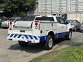 A 2017 Chevrolet Colorado pickup truck with a white body and blue accents parked with a utility bed and equipment rack on the back