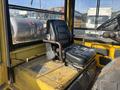 A black leather seat on a yellow industrial forklift with a metal support structure and control levers visible in the foreground