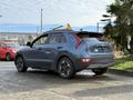 A 2023 Kia Niro EV in a blue-gray color parked with its rear view visible featuring distinctive taillights and modern design elements