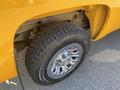 Close-up of a chrome wheel and tire on a yellow 2013 Chevrolet Silverado 1500 showing tread pattern and details of the wheel design