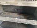 A 2015 Ford F-550 with a spacious empty storage compartment featuring two shelves both covered in dust and dirt