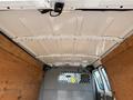 Interior view of a 2013 Ford Econoline van showing a spacious cargo area with wooden paneling and a metal partition near the front