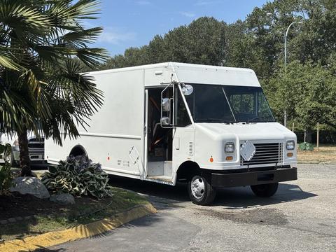 A white 2012 Ford Econoline is parked with its driver's side door open showcasing a boxy shape and large front grille