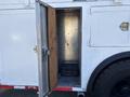 A 2006 Freightliner M2 106 with an open metal compartment door revealing a black storage container inside