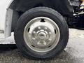 Close-up of a silver aluminum wheel rim with visible bolts and a black tire featuring a tread pattern on a 2000 Ford F-450