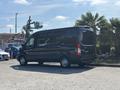 A black 2025 Ford Transit T-350 van parked at an angle showcasing its side profile and large windows