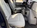 Interior view of a 2011 Ford Econoline showing two gray front seats and a center console with cup holders
