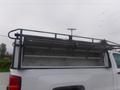 A 2015 Chevrolet Silverado 1500 with a truck bed rack and an open tool box in the bed displaying shelving for storage