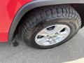 A close-up view of a silver alloy wheel with a rugged tire on a 2015 Jeep Grand Cherokee