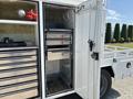 A 2017 Ford F-550 with an open storage compartment featuring metal drawers and tool racks arranged for organization