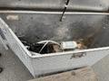A silver metal storage compartment of a 2016 Continental cargo trailer containing various items such as a canister tools and debris