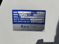 A blue inspection label on a white surface detailing the make model unit number serial number date of inspection and next inspection due for a vehicle
