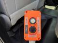 An orange Bucher hydraulics control box with buttons labeled for up and down functions