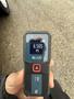 A person holding a Bosch Blaze laser distance measure displaying a measurement of 6.565 ft
